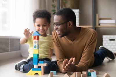 Photo of dad with toddler who is stacking wooden blocks