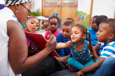 African American daycare teacher reading to children