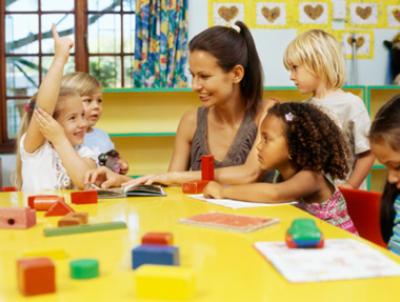 daycare teacher teaching kids at a yellow table