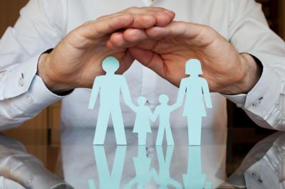 Image of hands covering paper cutout of family