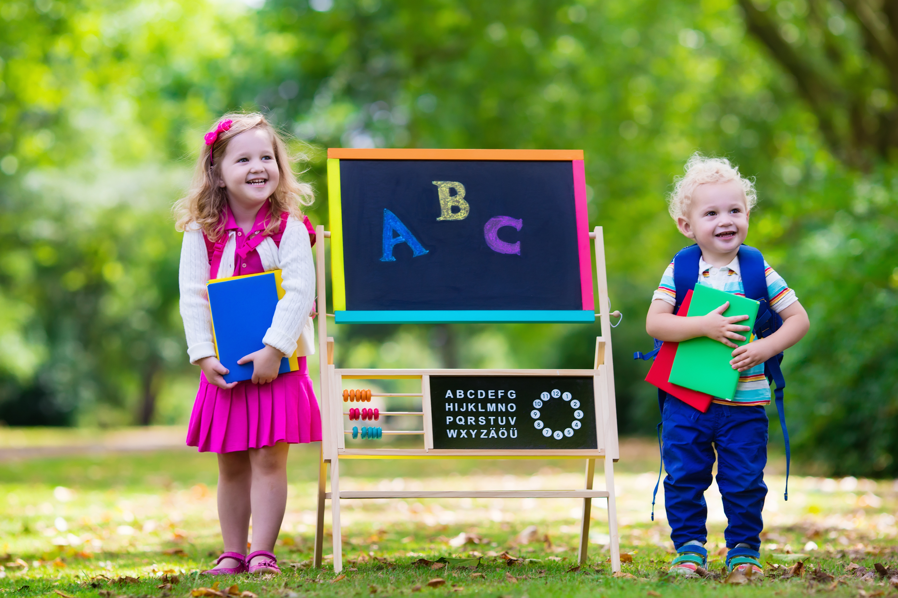 two children standing next to a chalkboard