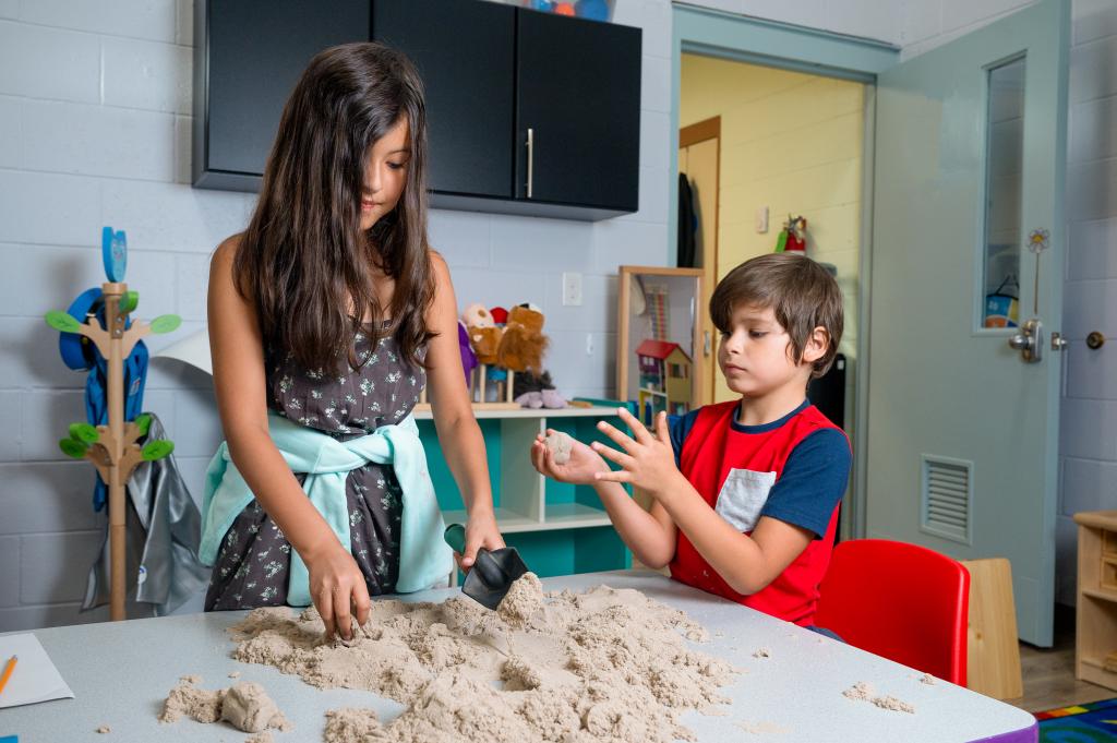 two children playing with sand while at daycare