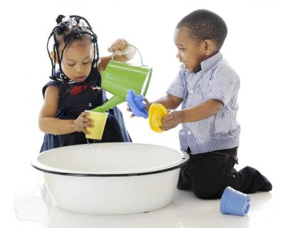 African-American children playing with watering can and plastic toys.