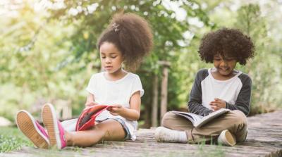 Two African American children reading outdoors