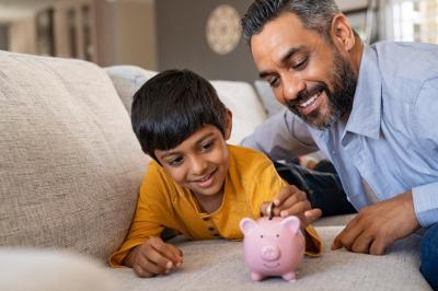 dad with son, putting money in piggy bank