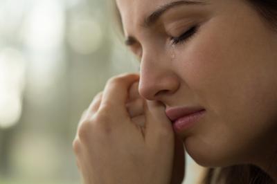 Image of woman crying, with her hand on her cheek.
