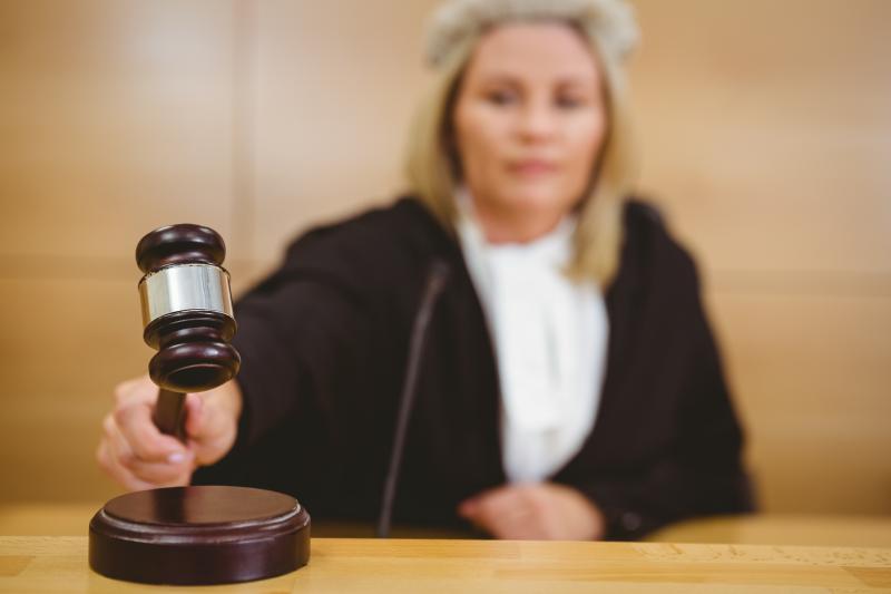 A female judge holds a gavel. 