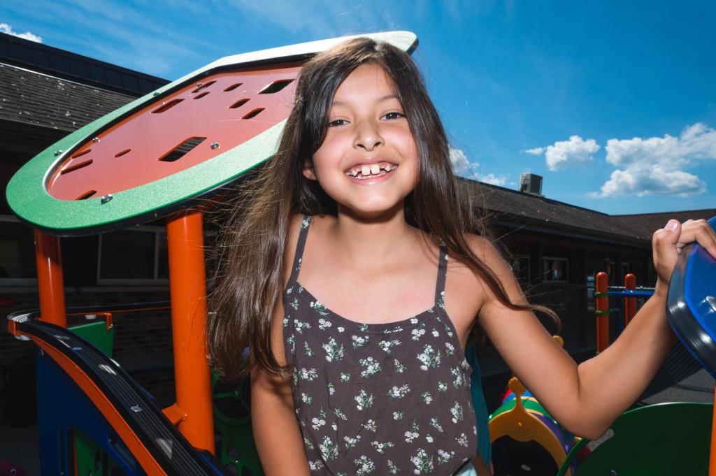A young Native American child smiling while on the playground.