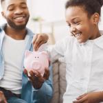 dad and daughter putting a coin in a piggy bank