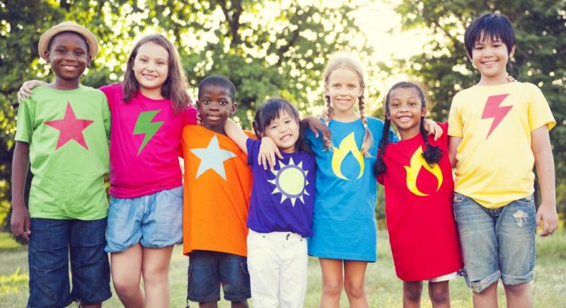 A diverse group of children, arms around each other with brightly-colored t-shirts